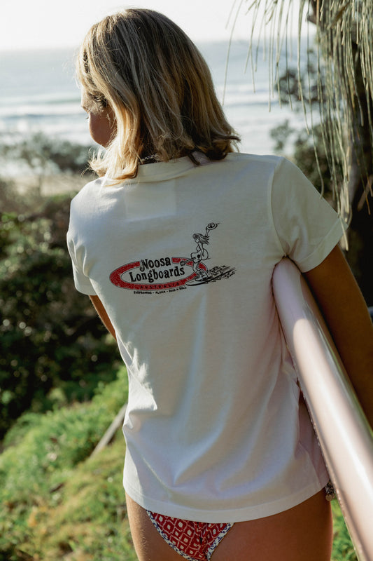 Rear graphic of Womens Shealoha 2k25 worn while carrying a pink surfboard near Sunshine Beach
