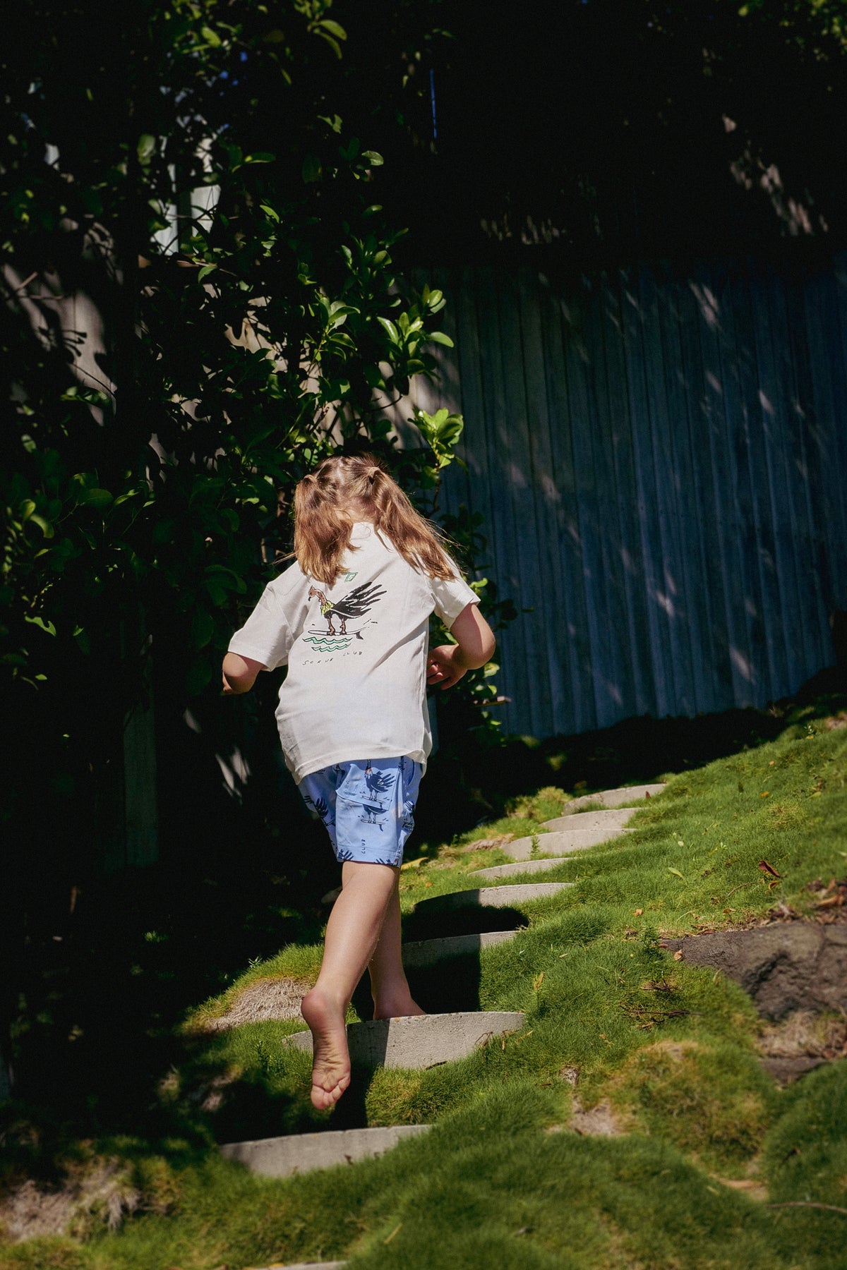 NL Kids Scrub Club Tee – White worn walking down the garden steps at Domic, Sunshine Beach