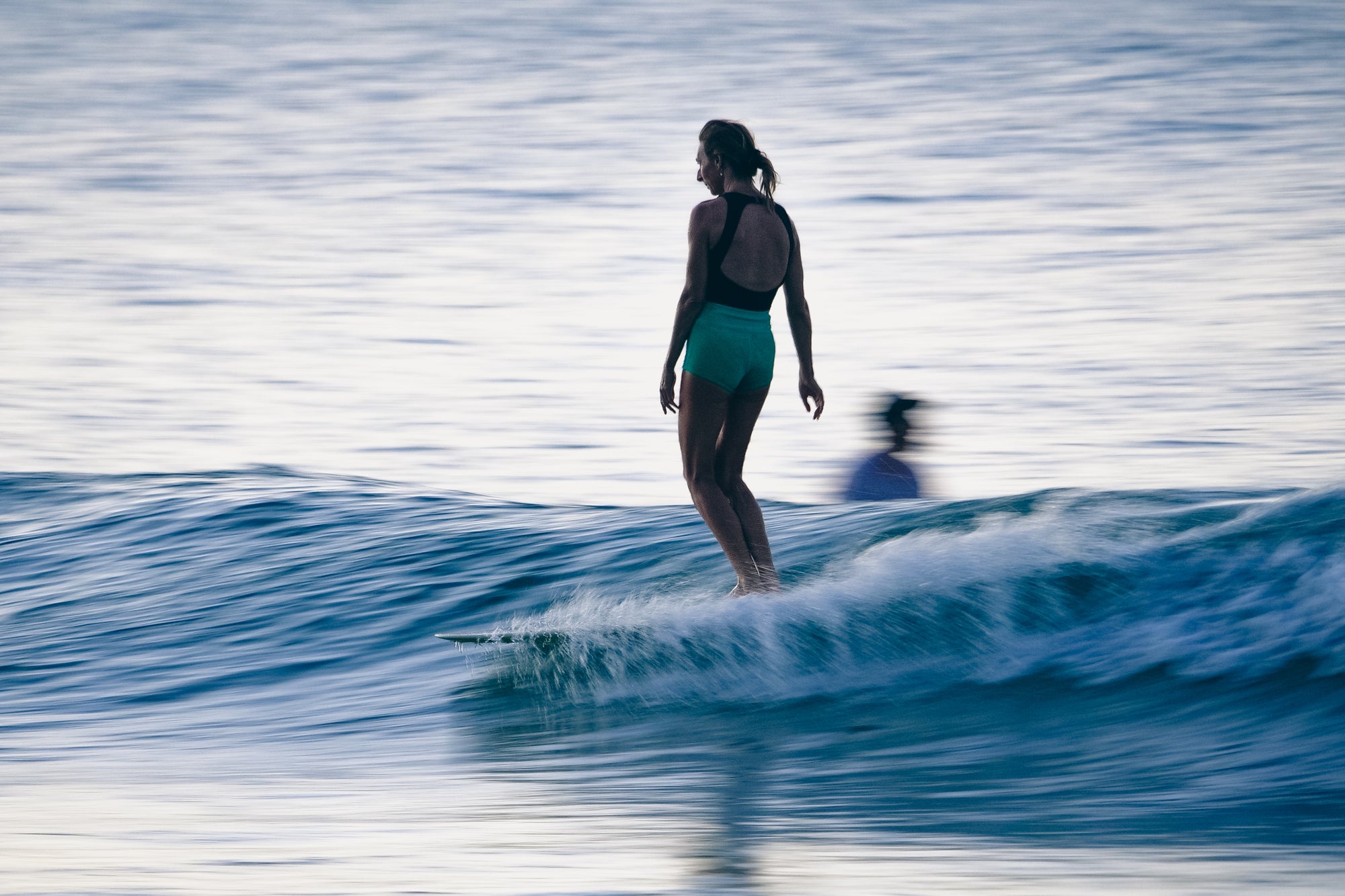 A woman longboarding across a small coastal wave