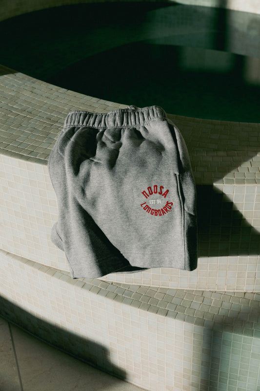 Folded NL Established Track Shorts Grey Marle with red Established print on a tiled seat at Domic