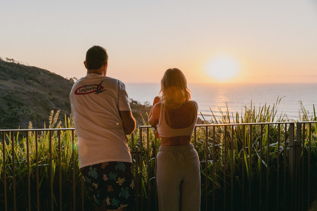 Rear view of NL Original Tee – White worn on the balcony at sunset at Domic, Sunshine Beach