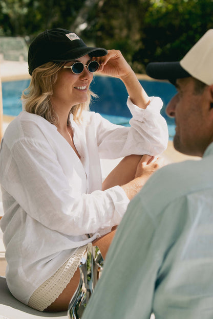 NL Patch Cap – Faded Black / OS worn with a white linen shirt poolside at Domic