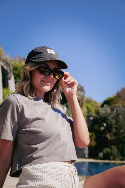 Front patch of NL Patch Cap – Faded Black / OS worn beside the pool at Domic