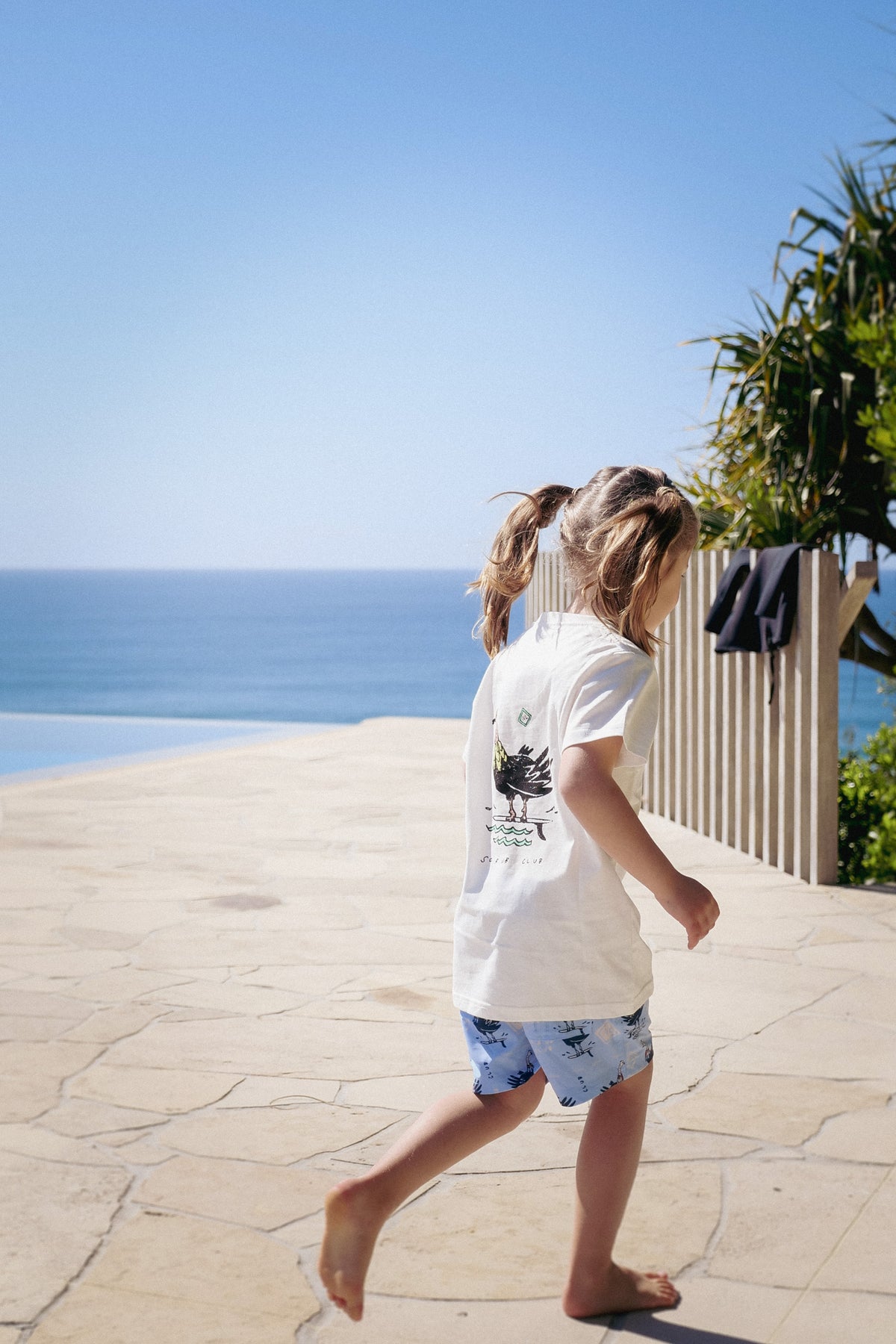 Rear turkey graphic of NL Kids Scrub Club Tee – White worn beside the pool at Domic