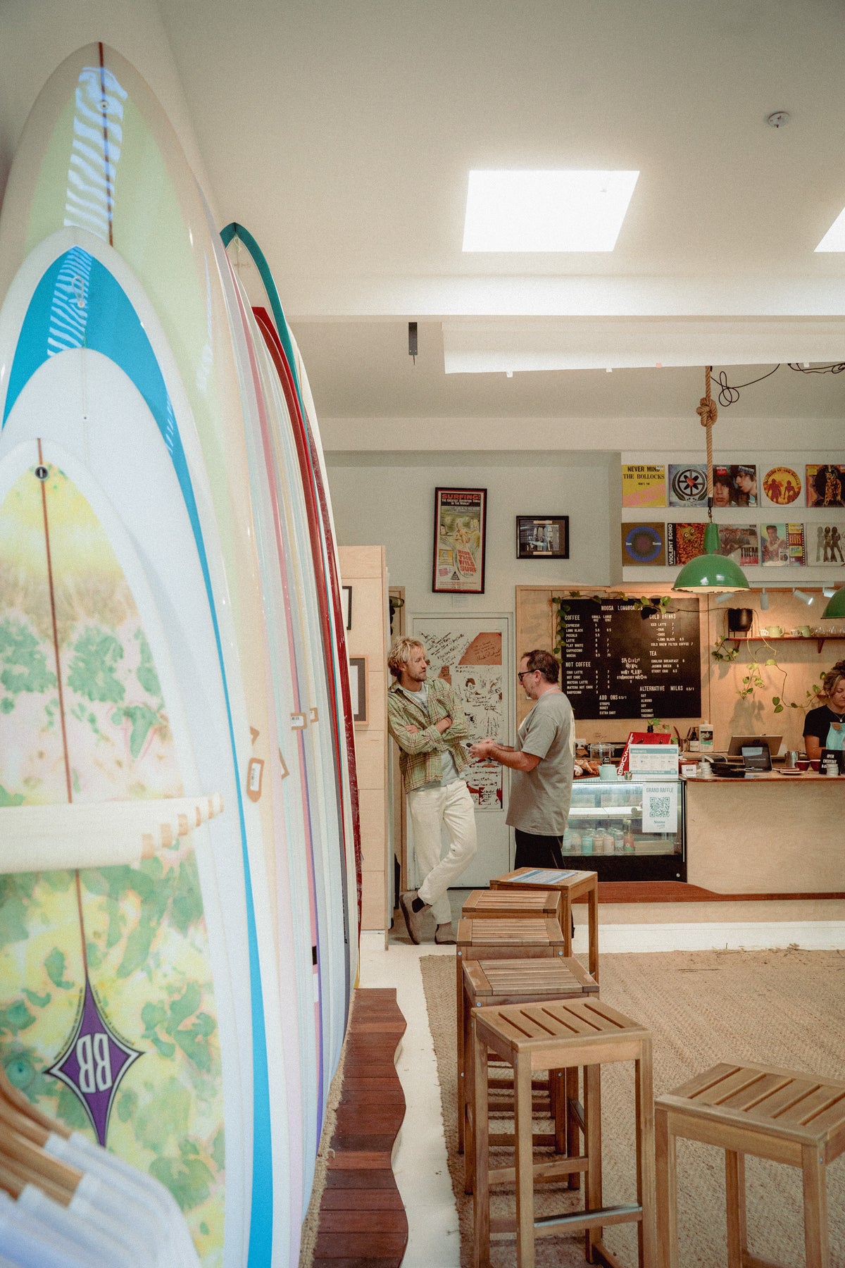 Conversation beside the coffee counter and surfboard racks at Noosa Longboards